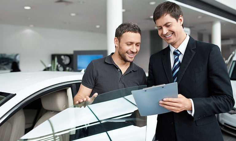 Car buyer overlooking details with salesperson at dealership